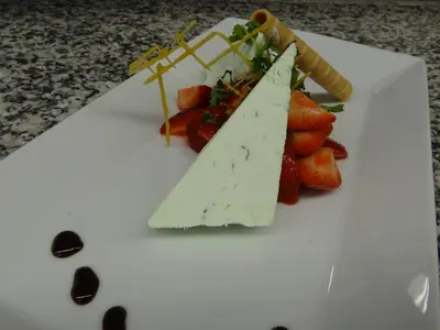 a white plate with a piece of cheese and vegetables at Herisau Swiss Quality Hotel in Herisau