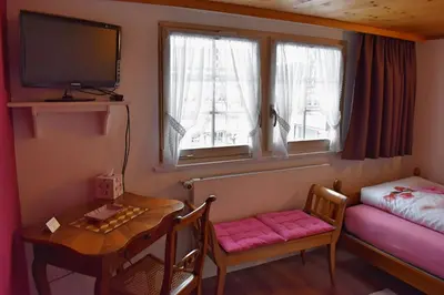 a small room with a table and a small room with a bed and a television at Gasthaus Sternen in Degersheim