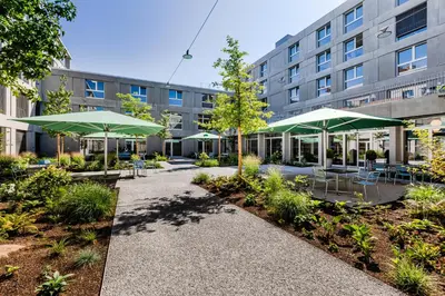a courtyard with tables and umbrellas in front of a building at Giesserei in Arbon