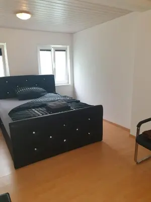 a black bed in a room with a chair at 3 Doppel Zimmer Apartement in 9320 Arbon in Arbon
