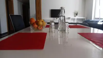 a table with a bowl of oranges and a vase of fruit at 3 Doppelbett Business Apartment am Bodensee in Arbon