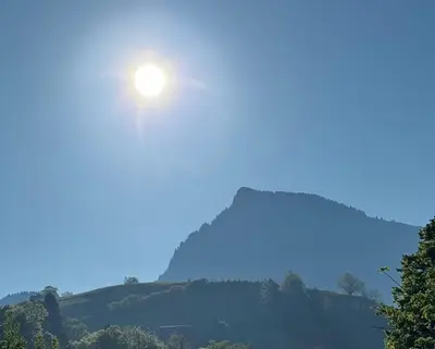 a sun rising over a mountain with trees at Zwinglis Ferienwohnung Klärli in Nesslau