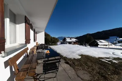 a table and chairs on a porch with snow at Sonnhalde in Wildhaus