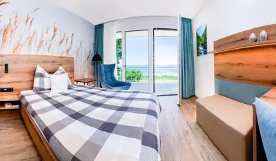 a view of a lake from between two trees at Hotel Restaurant Sokrates in Güttingen