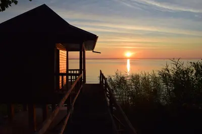 a house on a dock with the sunset in the background at Hotel Restaurant Sokrates in Güttingen