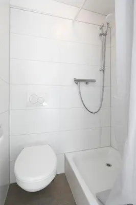 a white bathroom with a toilet and a shower at Hotel Untertor by Maier - Self-Check-in in Altstätten