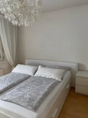 a bed in a room with a chandelier at over-night City-Flat in St. Gallen