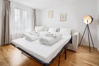a white room with a bed and a lamp at VISIMO Apartments Felsenstrasse St Gallen - Elegant heritage building in a quiet neighbourhood in St. Gallen
