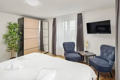 a hotel room with a bed and two chairs at VISIMO Apartments Felsenstrasse St Gallen - Elegant heritage building in a quiet neighbourhood in St. Gallen