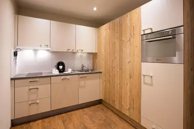 a kitchen with white cabinets and a wooden wall at Wohntel - wohnen wie im Hotel in Sevelen