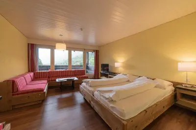 a large bedroom with two beds and a couch at Hotel Säntis Lodge in Unterwasser