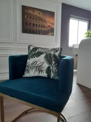 a blue chair in a living room with a pillow at Rome Apartment in Rheineck