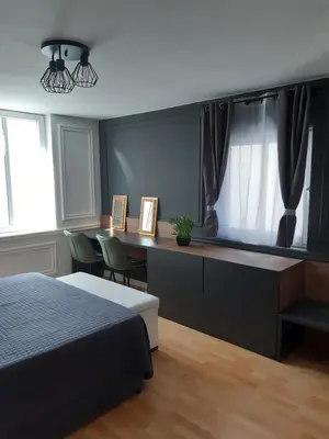 a bedroom with a bed and a desk and windows at Rome Apartment in Rheineck