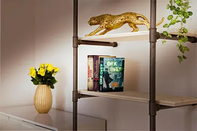 a shelf with a book and a vase of flowers at VISIMO Apartments Lehnstrasse St Gallen - Stylish, Smart, Connected in St. Gallen