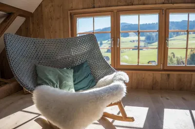 a teddy bear sitting in a rocking chair with a pillow at NEU renoviert - Bitzi Appenzell – Mit Aussicht in Appenzell