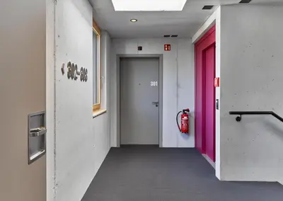 a hallway with a pink door and a fire extinguisher at BoHo by Maier - kontaktloser Check-In in Buchs