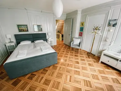 a bedroom with a large bed and a wooden floor at CityLodge St Gallen - 2 min to Marktplatz in St. Gallen