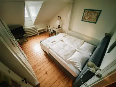 a bedroom with a white bed and a wooden floor at CityLodge St Gallen - 2 min to Marktplatz in St. Gallen