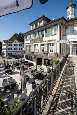 a hotel with tables and umbrellas in front of a building at Hotel Krone Gais in Gais