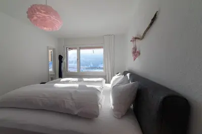 a white bedroom with a bed and a window at Panorama Blick in Unterwasser