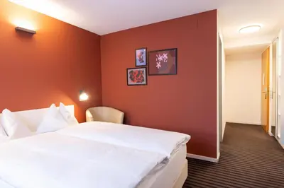 a hotel room with a white bed and orange walls at Self Check-In Hotel David 22 in St. Gallen