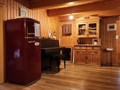 a kitchen with a refrigerator and a piano at Backpacker Bären in Urnäsch