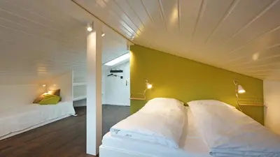 a bedroom with a white bed with a yellow wall at Alte Metzg - Boutique Pension in Appenzell