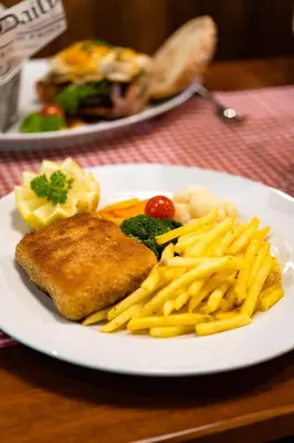 a white plate with fish and french fries on a table at Hotel Sternen Unterwasser in Unterwasser