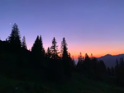 a sunset in the mountains with trees in the foreground at Hotel Sternen Unterwasser in Unterwasser