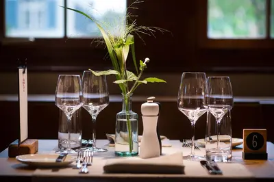 a table with wine glasses and a vase with a plant in it at Gasthaus zum Trauben in Weinfelden