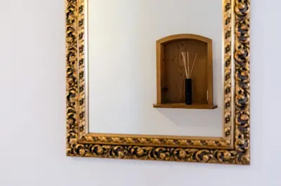 a mirror on a wall with a vase with sticks at Blattenheimat - im traditionellen Appenzeller Haus in Appenzell