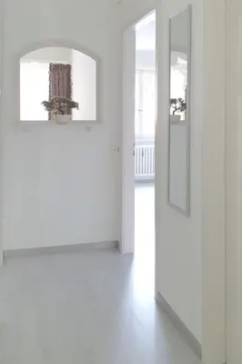 a white room with a door and a mirror at Bright and modern apartment in the heart of Altstätten in Altstätten