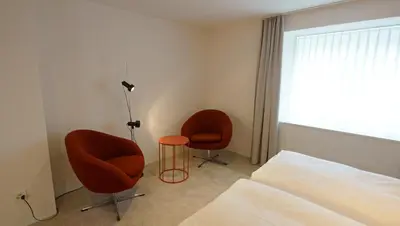 a bedroom with two chairs and a bed and a window at Alte Metzg - Hostel in Appenzell