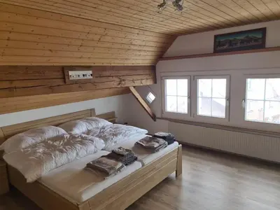 a large bed in a room with a wooden ceiling at Alpen-Paradies Edelweiss in Urnäsch