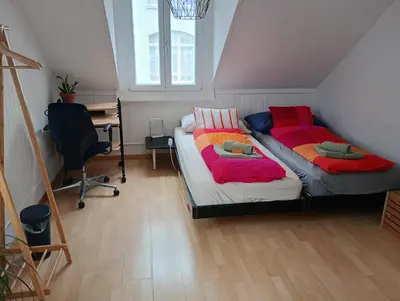 a bedroom with two beds and a desk in it at Gemütliche Dachwohnung in St. Gallen