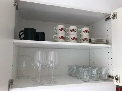 a shelf with wine glasses and cups on it at INN JOY Apartments - Sankt Gallen Lachen in St. Gallen