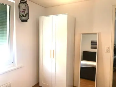 a white cabinet in a room with a mirror at INN JOY Apartments - Sankt Gallen Lachen in St. Gallen