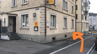 a building on a street with an orange arrow pointing towards it at INN JOY Apartments - Sankt Gallen Lachen in St. Gallen