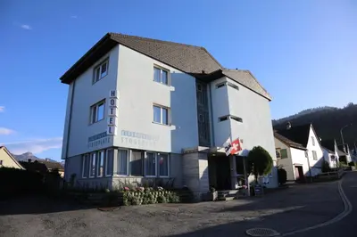 a bedroom with a bed and a chair and a window at Hotel B&B Stossplatz anytime and easy self Check-in in Appenzell