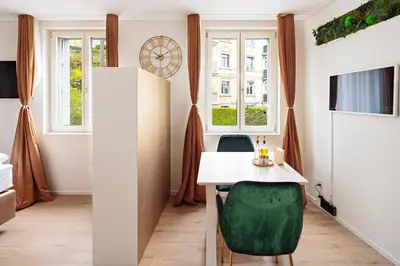 a dining room with a white table and green chairs at VISIMO Apartments Mühlensteg St Gallen - Elegant Quiet Central in St. Gallen