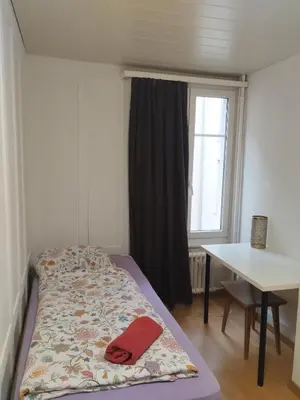 a bed in a room with a table and a window at City Home St Gallen in St. Gallen