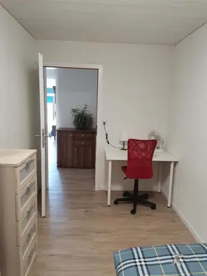 a bedroom with a desk and a red chair at City Home St Gallen in St. Gallen