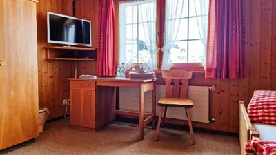 a desk with a chair and a television in a room at Gasthaus Rössli in Brülisau