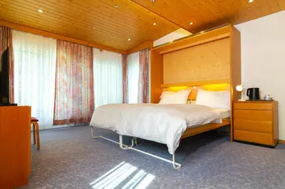 a bedroom with a large bed with a wooden headboard at Hotel Swiss Views in Hemberg