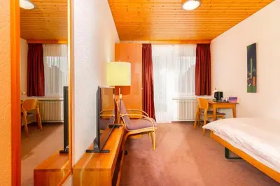 a bedroom with a bed and a television and a desk at Hotel Swiss Views in Hemberg