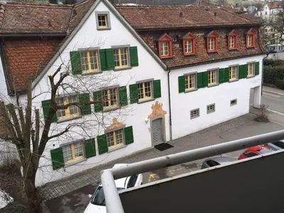 a large white building with green shuttered windows at 2 rooms with balcony, central, quiet location in St. Gallen