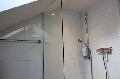 a shower with a glass door in a bathroom at Completely renovated apartment near the train station and the center in St. Gallen