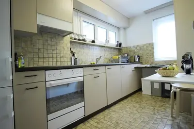 a large kitchen with white appliances and a table at Casa Schilling- 2,5 rooms with balcony near hospital, university in St. Gallen