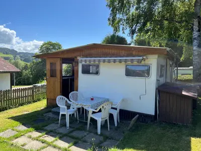 a small caravan with a table and chairs in a yard at Camping Schönengrund in Schönengrund