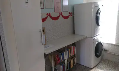 a kitchen with a refrigerator and a shelf with books at Camping Schönengrund in Schönengrund